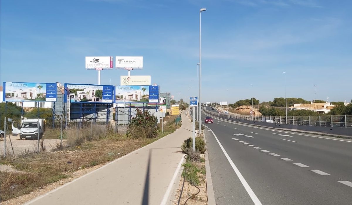 vallas publicitarias en Carretera. Valla publicitaria de marco azul junto a una carretera en un paisaje mediterráneo.